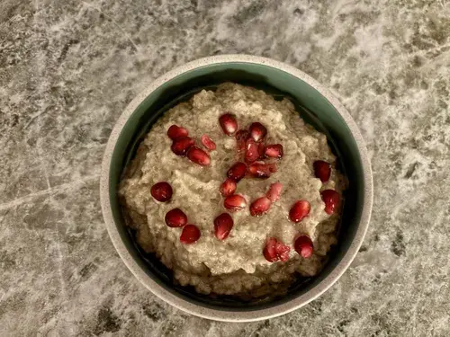 Baba ghanoush dip i en skål med olivenolie og granatæblekerner